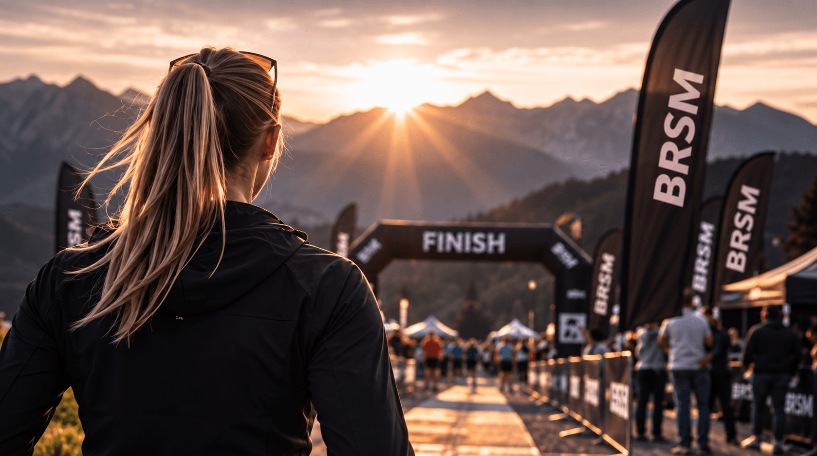 Frau blickt bei Sonnenaufgang auf den Zielbogen eines Bergsportevents