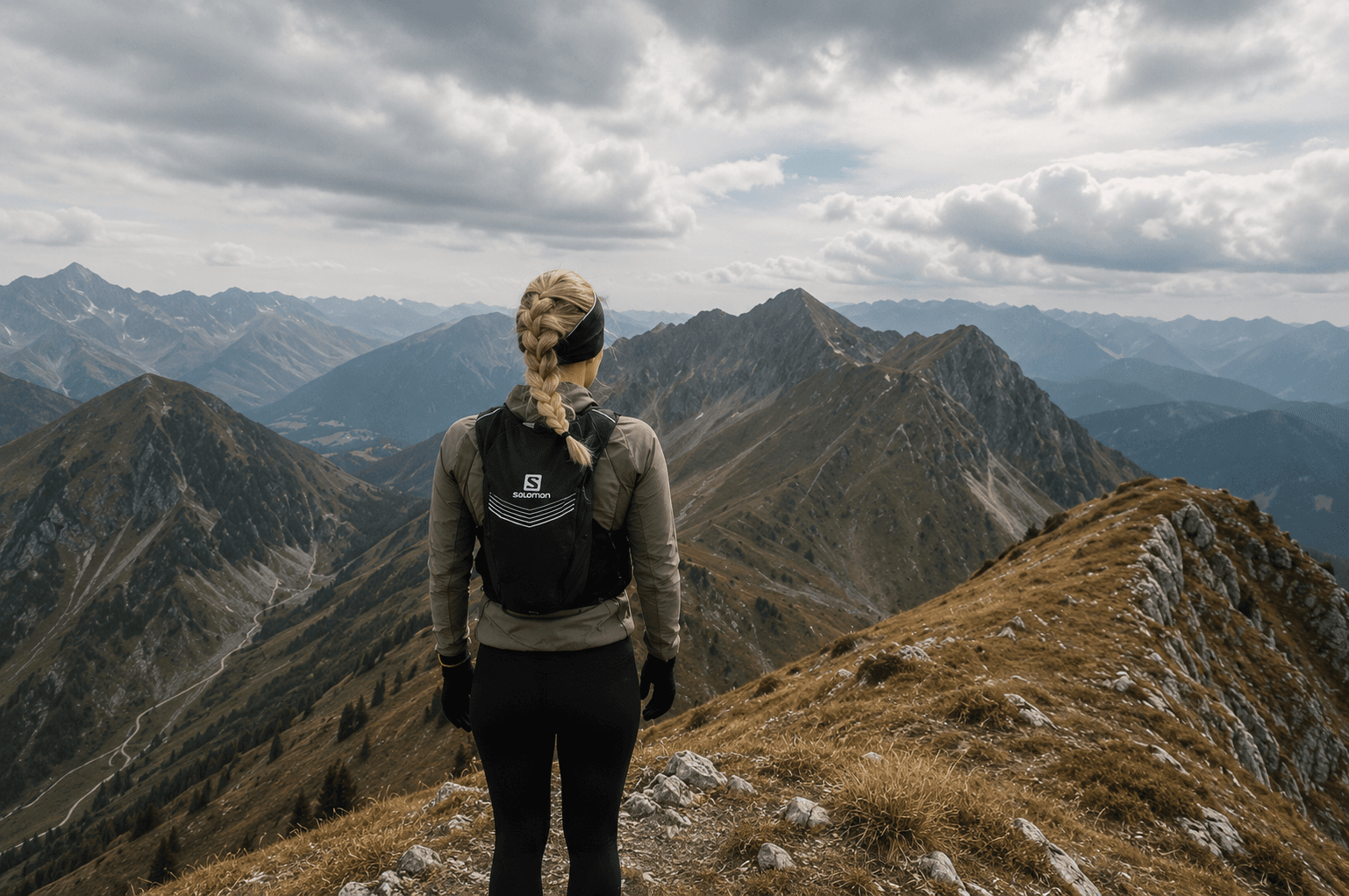 Wanderin mit Rucksack blickt über ein Bergpanorama